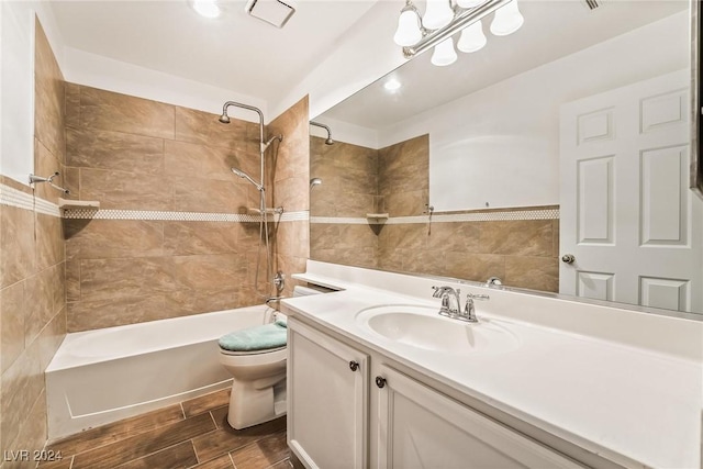 full bathroom with tiled shower / bath, vanity, and toilet