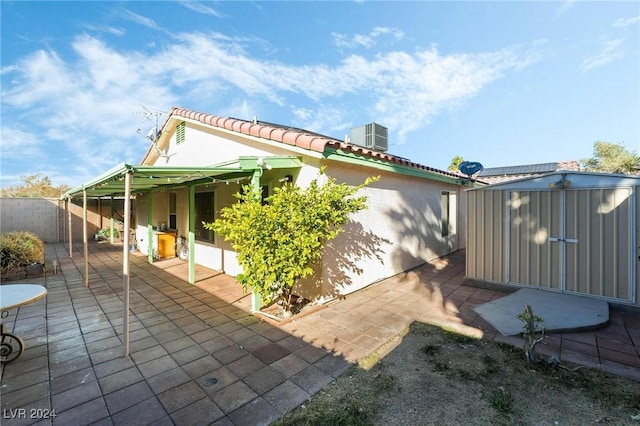 view of side of property with a shed, central AC unit, and a patio area