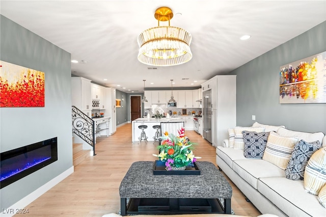 living room with light wood-type flooring and an inviting chandelier