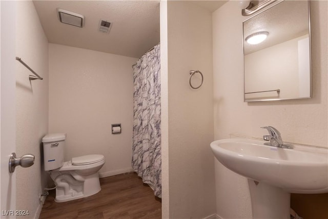 bathroom featuring hardwood / wood-style flooring, a shower with curtain, toilet, and sink