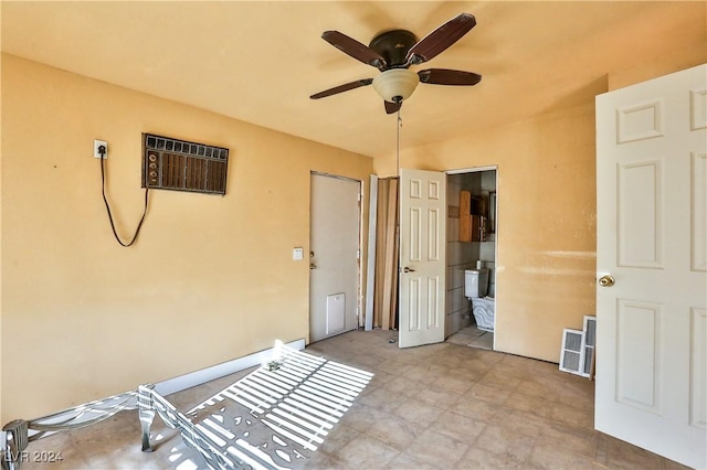 unfurnished bedroom with a wall unit AC, connected bathroom, and ceiling fan