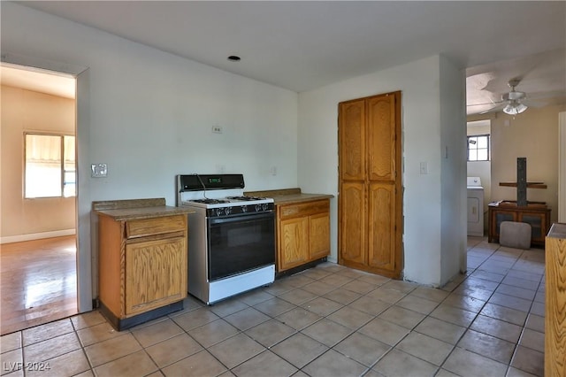 kitchen featuring washer / dryer, white range with gas cooktop, a healthy amount of sunlight, and ceiling fan