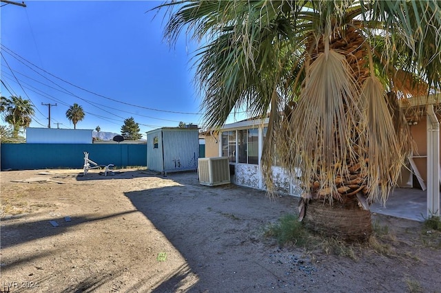 view of yard with central AC unit and a storage shed