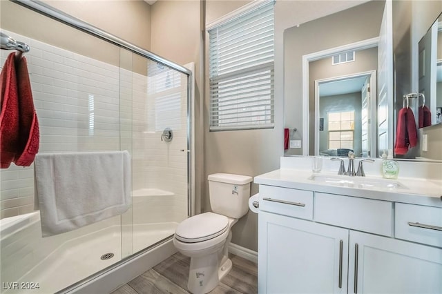 bathroom with toilet, hardwood / wood-style floors, vanity, and walk in shower