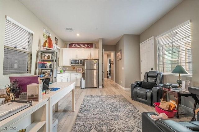 kitchen with a wealth of natural light, white cabinetry, light hardwood / wood-style floors, and appliances with stainless steel finishes