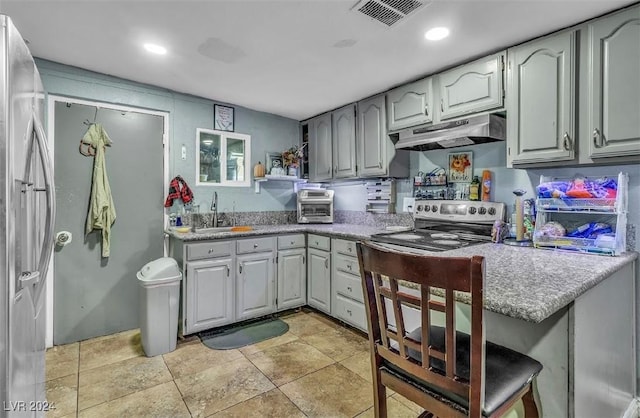 kitchen with sink, gray cabinets, appliances with stainless steel finishes, a kitchen bar, and kitchen peninsula