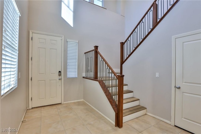 foyer with a wealth of natural light, light tile patterned floors, and a high ceiling