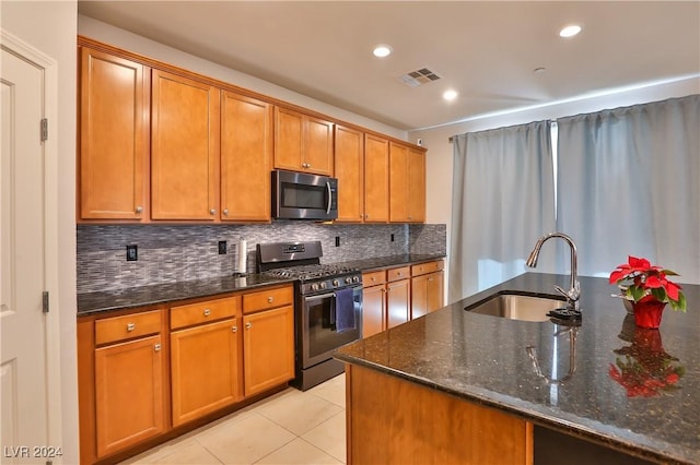 kitchen featuring decorative backsplash, appliances with stainless steel finishes, dark stone counters, sink, and light tile patterned floors