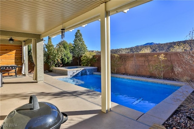 view of pool with an in ground hot tub, a mountain view, and a patio area