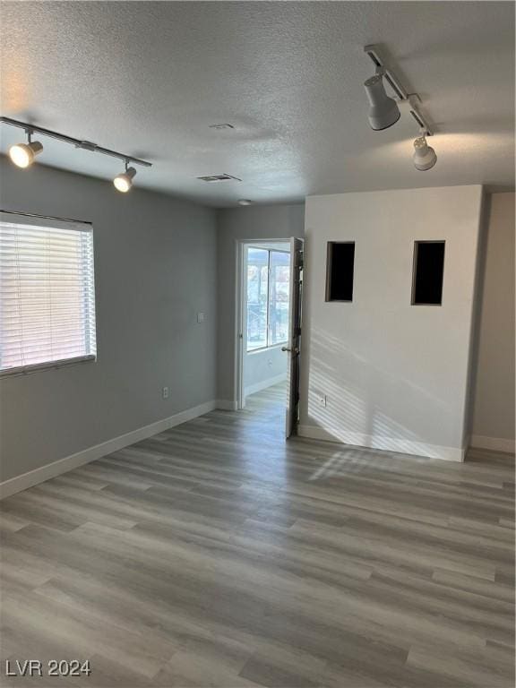 unfurnished room with hardwood / wood-style floors, a textured ceiling, and track lighting