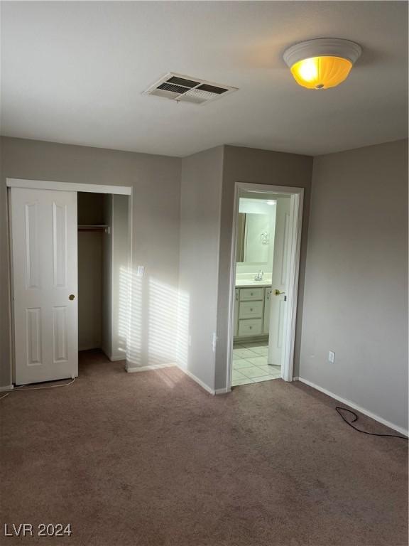 unfurnished bedroom featuring carpet, connected bathroom, and a closet