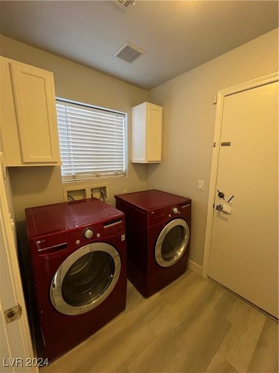 laundry room with washer and clothes dryer, light hardwood / wood-style floors, and cabinets