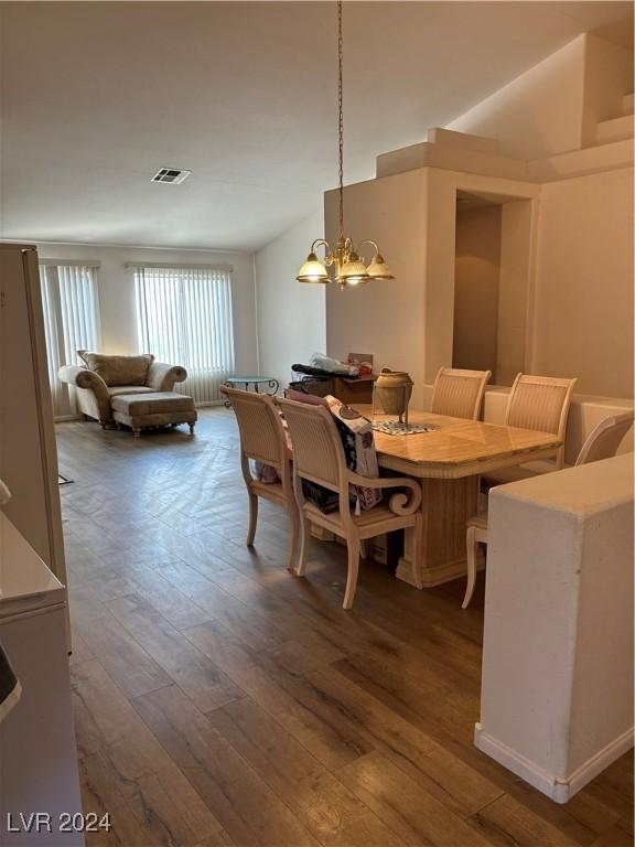 dining room featuring dark hardwood / wood-style floors, a notable chandelier, and vaulted ceiling