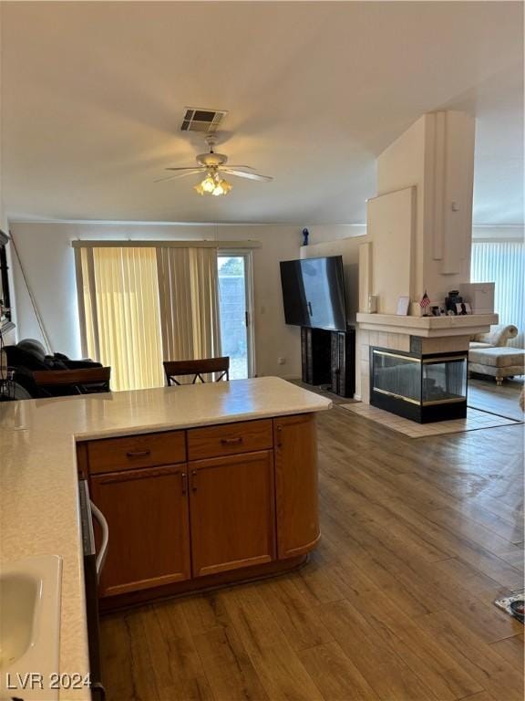 kitchen with ceiling fan, hardwood / wood-style flooring, a tile fireplace, and sink