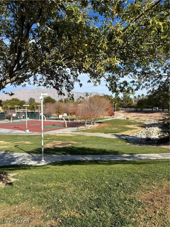 surrounding community featuring a mountain view, a lawn, and basketball hoop