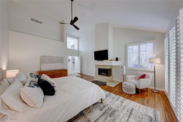 bedroom with hardwood / wood-style floors, high vaulted ceiling, and ceiling fan