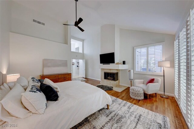 5035 Shoal Creek Cir, Las Vegas, NV 89113 - bedroom featuring a tiled fireplace, multiple windows, wood finished floors, high vaulted ceiling, and baseboards