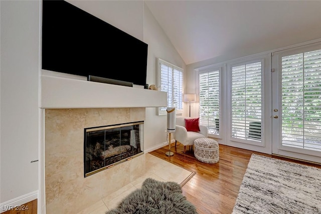 living area with wood-type flooring, a fireplace, and vaulted ceiling