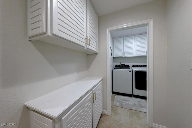 laundry room featuring washer and dryer, light tile patterned flooring, and cabinets