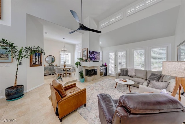 living room featuring ceiling fan with notable chandelier, light tile patterned floors, and a towering ceiling