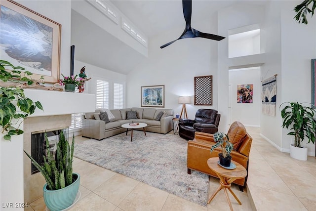 living room featuring ceiling fan, a fireplace, high vaulted ceiling, and light tile patterned floors