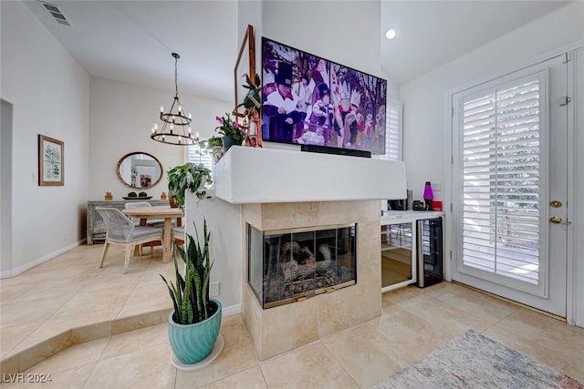 living room featuring a tile fireplace, tile patterned flooring, and an inviting chandelier