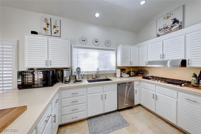 kitchen with stainless steel appliances, vaulted ceiling, sink, white cabinets, and light tile patterned flooring