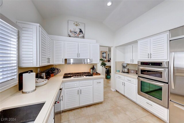 kitchen featuring light tile patterned floors, stainless steel appliances, white cabinetry, and lofted ceiling