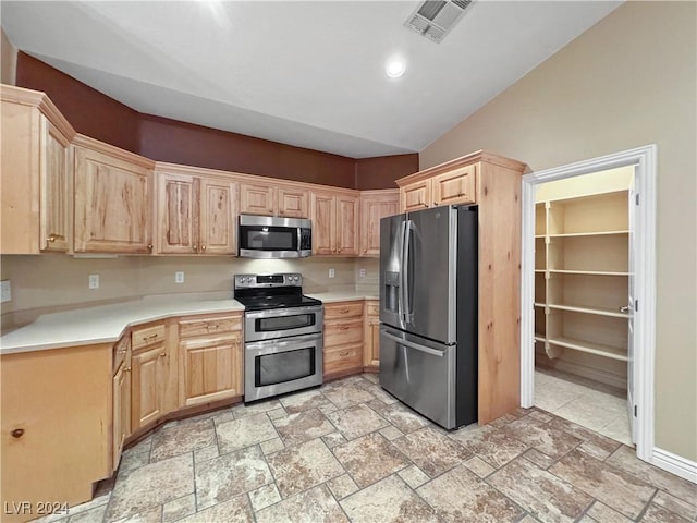 kitchen with light brown cabinets, stainless steel appliances, and vaulted ceiling