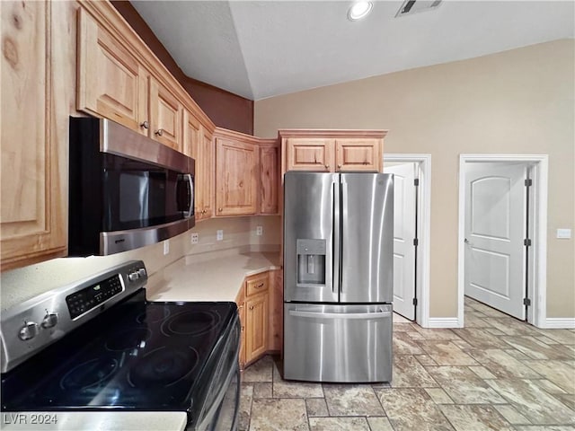 kitchen with light brown cabinets, lofted ceiling, and stainless steel appliances