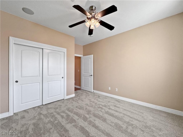 unfurnished bedroom with ceiling fan, a closet, and light carpet