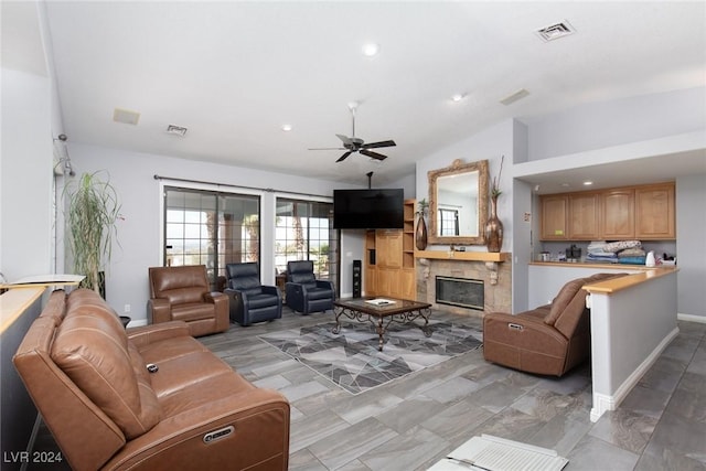 living room with ceiling fan, a fireplace, and vaulted ceiling