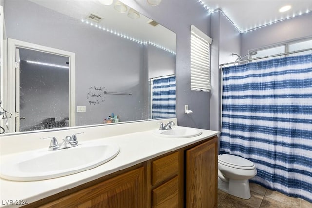 bathroom with a shower with shower curtain, tile patterned floors, a wealth of natural light, vanity, and toilet