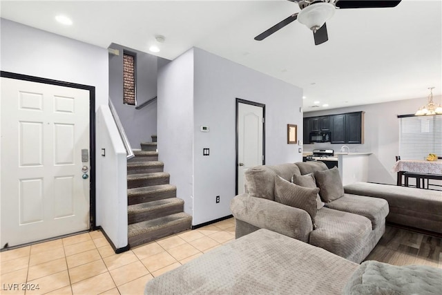 tiled living room featuring ceiling fan with notable chandelier