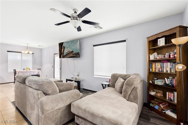 living room with ceiling fan with notable chandelier and light wood-type flooring