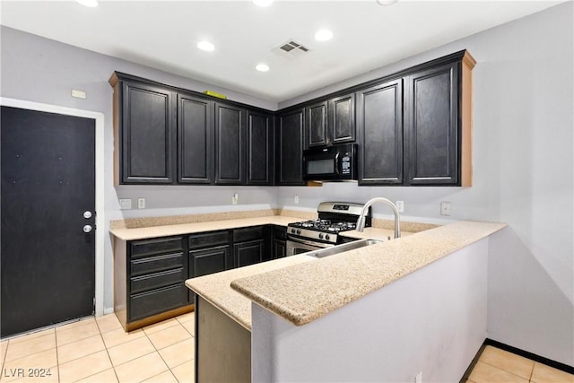 kitchen featuring sink, light tile patterned floors, gas stove, light stone counters, and kitchen peninsula