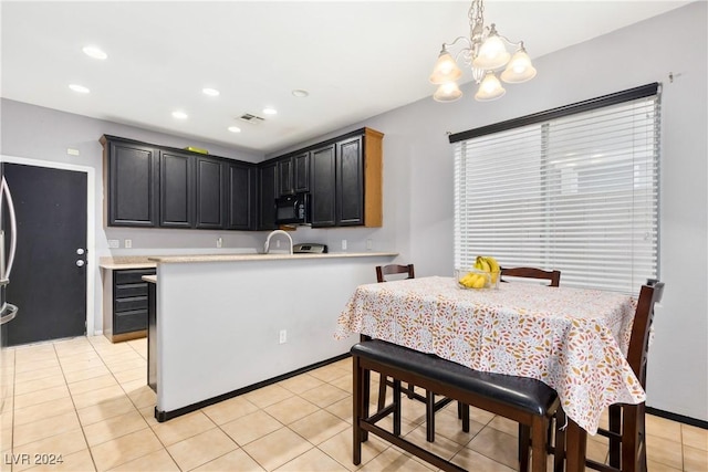 kitchen featuring a chandelier, an island with sink, hanging light fixtures, and light tile patterned flooring