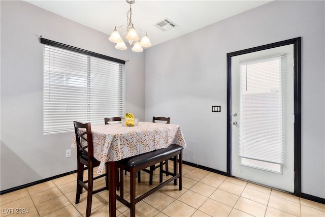 tiled dining room featuring a healthy amount of sunlight and an inviting chandelier