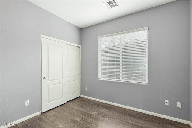 unfurnished bedroom with a closet, hardwood / wood-style flooring, and multiple windows