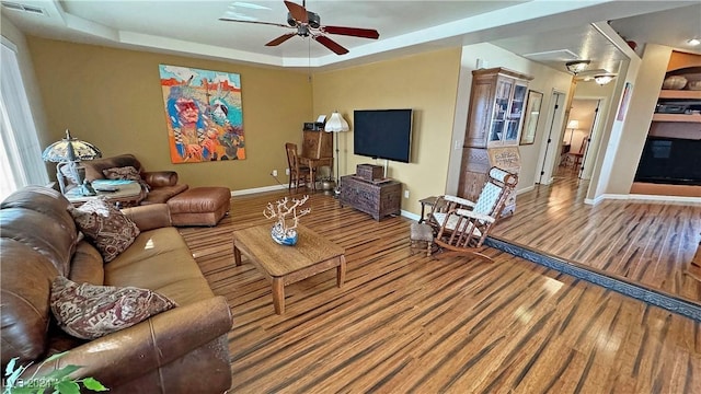 living room featuring a tray ceiling, ceiling fan, and hardwood / wood-style flooring