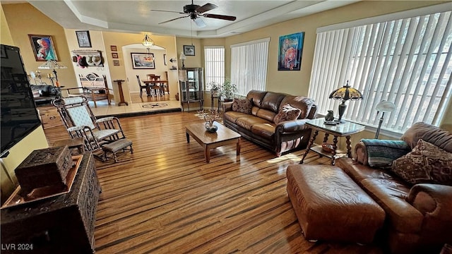 living room with hardwood / wood-style floors, a raised ceiling, and ceiling fan