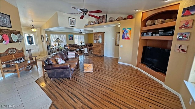 tiled living room featuring ceiling fan, built in features, and lofted ceiling