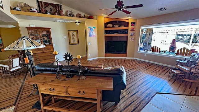 living room featuring ceiling fan, built in features, hardwood / wood-style floors, and vaulted ceiling