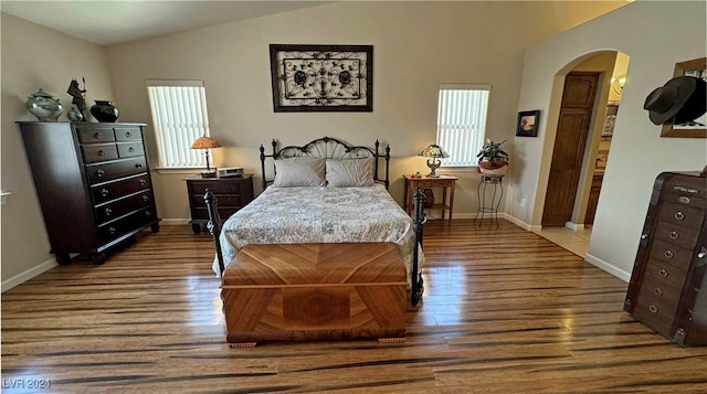 bedroom featuring multiple windows, hardwood / wood-style floors, and vaulted ceiling