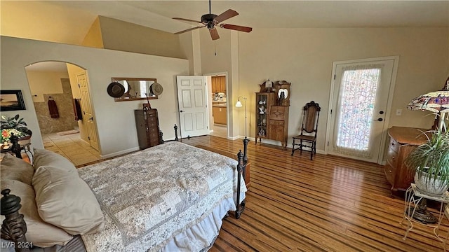 bedroom with ensuite bath, ceiling fan, wood-type flooring, and vaulted ceiling