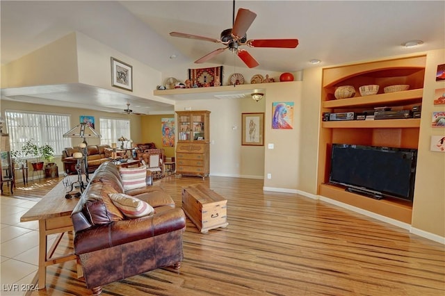 living room with ceiling fan, built in features, and vaulted ceiling