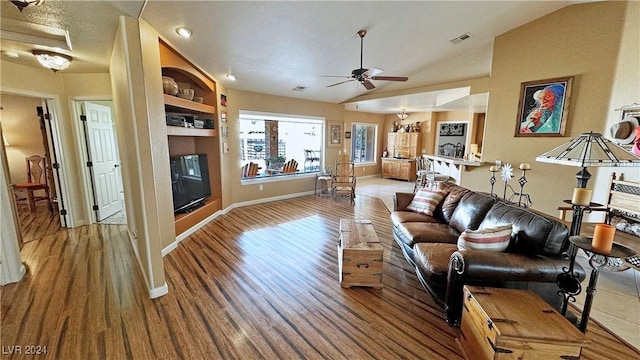 living room with built in shelves, ceiling fan, hardwood / wood-style floors, and lofted ceiling