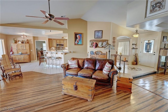 living room with ceiling fan, lofted ceiling, plenty of natural light, and light hardwood / wood-style flooring