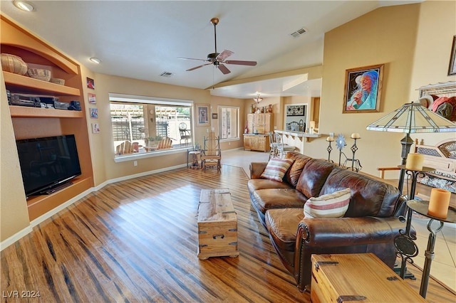 living room with built in shelves, vaulted ceiling, ceiling fan, and hardwood / wood-style floors