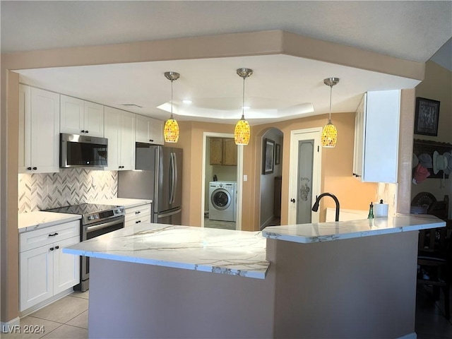 kitchen featuring tasteful backsplash, white cabinetry, washer / dryer, kitchen peninsula, and stainless steel appliances